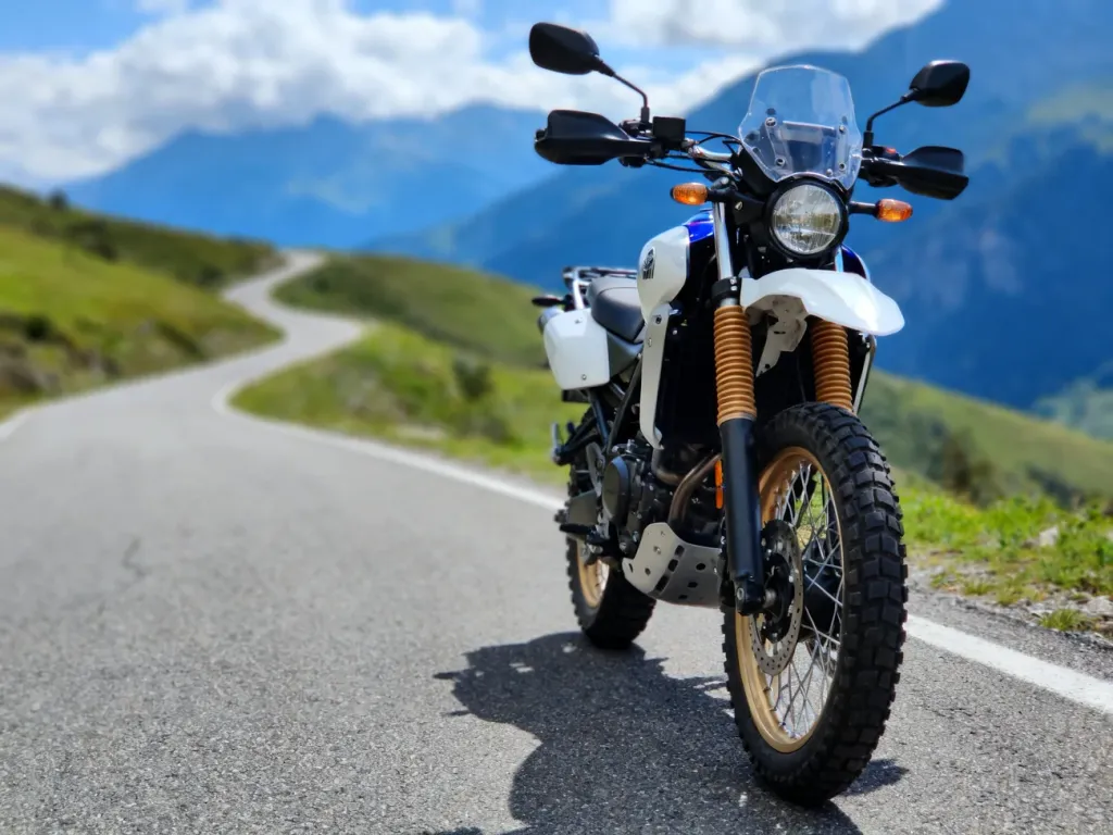 Niebieska Yamaha Tenere 700 na górskiej drodze, podkreślony przedni widelec, koło i zbiornik w scenerii krętej szosy.